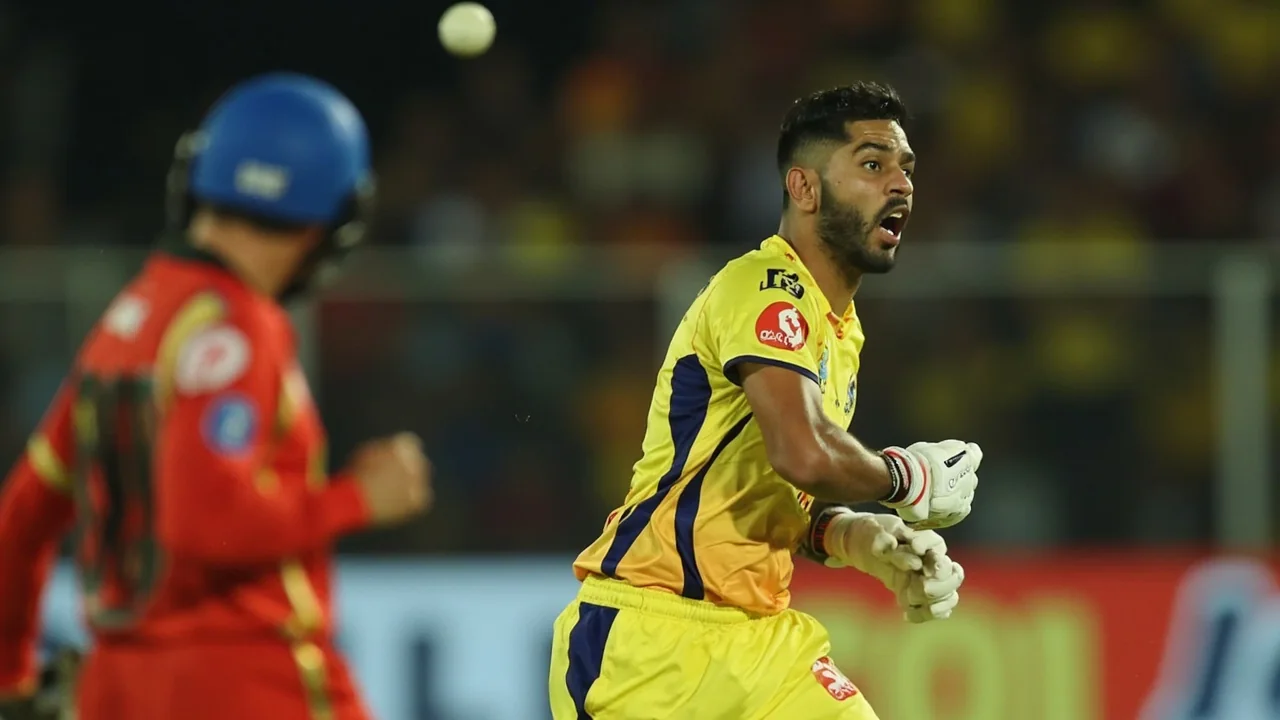 Side-on view of an IPL batter driving through the off side during an IPL match, with the ball in mid-flight and the fielding side visible in the background